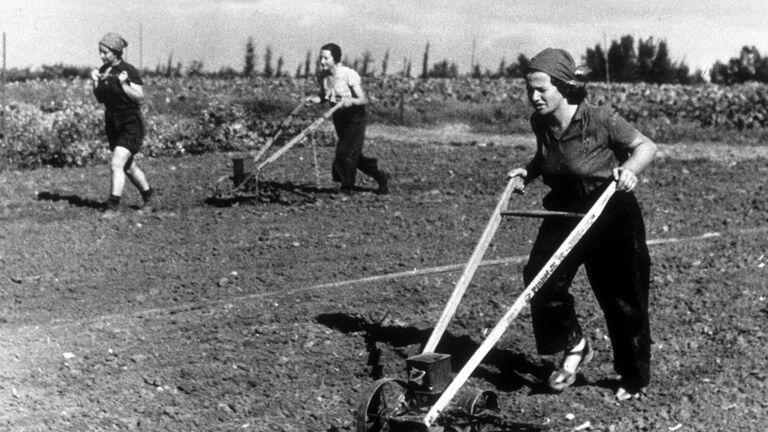 Women hand-plouging fields on a kibbutz in Israel