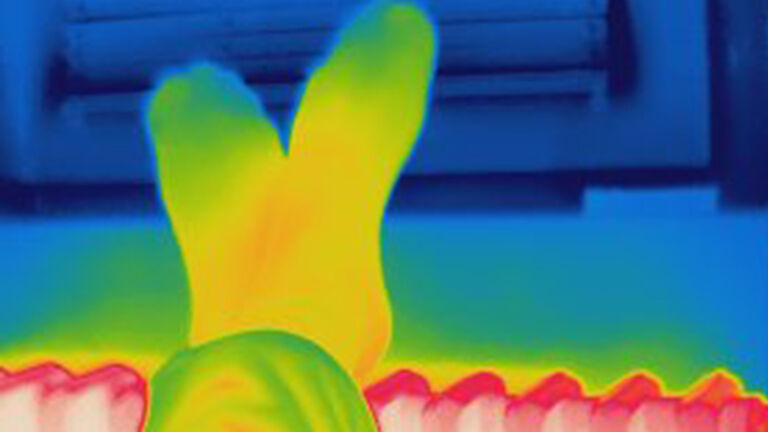 Thermal image of human warming legs on hot home radiator