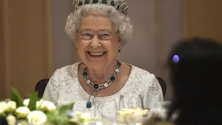 Queen Elizabeth II smiles as she attends a dinner