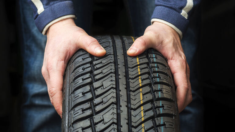 Closeup of mechanic hands holding a tire on dark background