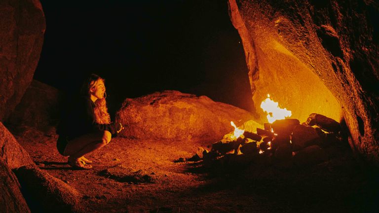 Young woman in front of camp fire at night in northern california