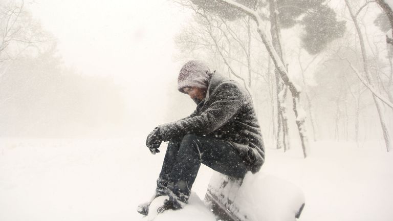 man sitting on bench snowy day