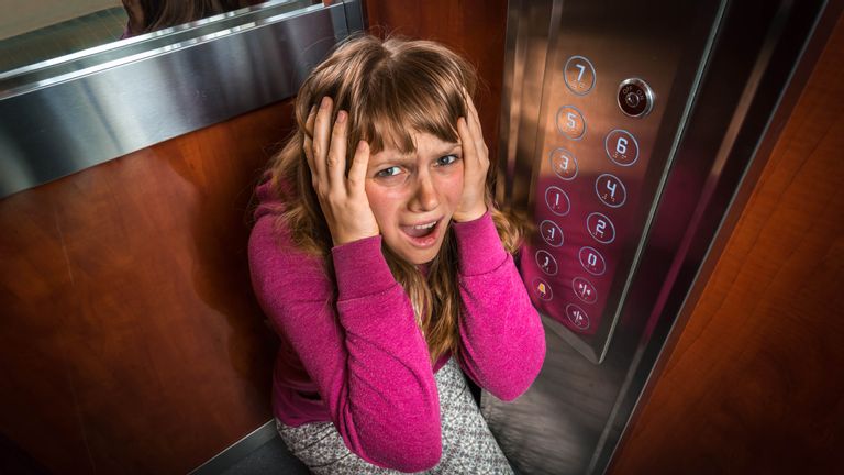 Shocked woman with claustrophobia in the moving modern elevator