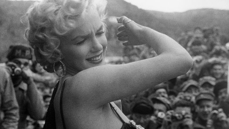 Marilyn Monroe shields her eyes from flashbulbs