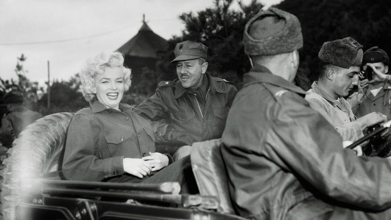 Marilyn Monroe rides a jeep with Brigadier General Robert Hobaboom